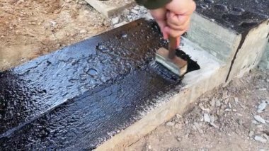 İnşaatçı daha fazla duvar döşemesi için beton temelin tepesine devasa bir astar uygular. 4K video ağır çekim. Temel su geçirmez inşaat çalışmaları