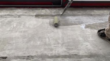Construction works. 4k video footage with priming the floor surface before further finishing work. The builder is priming the floor with a roller