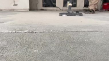 Construction works. The builder removes dust and small debris from the surface of the cement-sand screed using a vacuum cleaner for further finishing work. 4k video footage