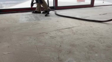 Construction works. The builder removes dust and small debris from the surface of the cement-sand screed using a vacuum cleaner for further finishing work. 4k video footage