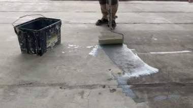 Construction works. 4k video footage with priming the floor surface before further finishing work. The builder is priming the floor with a roller