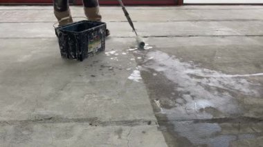 Construction works. 4k video footage with priming the floor surface before further finishing work. The builder is priming the floor with a roller