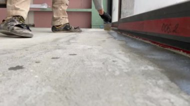 Construction works. 4k video footage with priming the floor surface before further finishing work. The builder is priming the floor with a brush