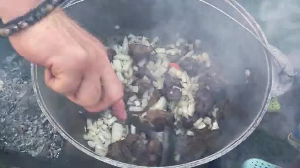 传统乌兹别克皮面包的烹调过程 一个男人在火上的大锅里做饭的特写镜头 慢动作视频4K 男人用洋葱煎肉 — 图库视频影像
