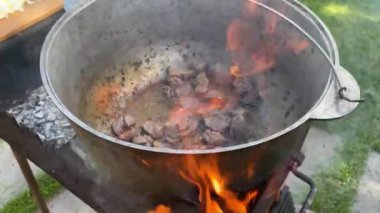 The process of cooking traditional Uzbek pilaf. Close-up footage of a man cooking pilaf in a cauldron on a fire. Video 4k. Man frying meat