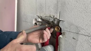 Plumbing work on installing the outlet of cold and hot water from the wall to connect the faucet to the sink. 4k video footage of construction work inside the building