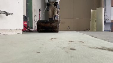 A builder glues a synthetic non-woven fabric onto a tile adhesive before laying the tiles on the floor. 4k video footage of the construction process, as a professional builder glues a special canvas