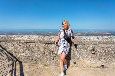 Young beautiful woman visits the sights of the Republic of San Marino, Italy. She stay in Second tower - Cesta and admiring the view of panorama of San Marino