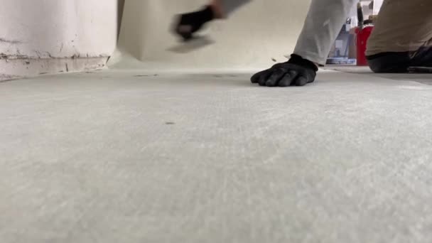 床にタイルを敷く前に 合成不織布をタイル接着剤に接着します 建設プロセスの4Kビデオ映像 プロの建築家として特別なキャンバスを接着します — ストック動画