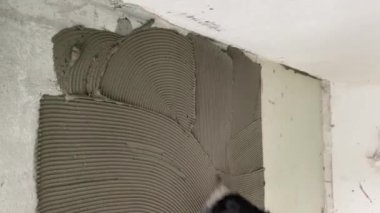 A builder glues a synthetic non-woven fabric onto a tile adhesive before laying the tiles on the floor. 4k video footage of the construction process, as a professional builder glues a special canvas