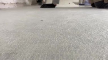 A builder glues a synthetic non-woven fabric onto a tile adhesive before laying the tiles on the floor. 4k video footage of the construction process, as a professional builder glues a special canvas
