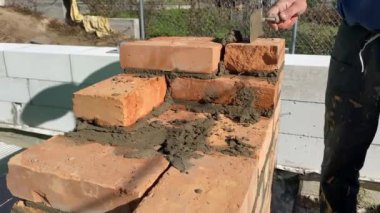 4k footage of a builder performing solid red brick masonry at a construction site using masonry mortar.