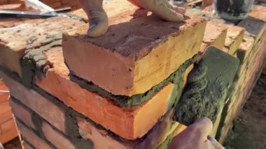 4k footage of a builder performing solid red brick masonry at a construction site using masonry mortar.