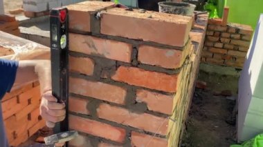 4k footage of a builder performing solid red brick masonry at a construction site using masonry mortar.