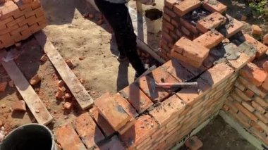 4k footage of a builder performing solid red brick masonry at a construction site using masonry mortar.