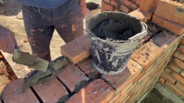 4k footage of a builder performing solid red brick masonry at a construction site using masonry mortar.