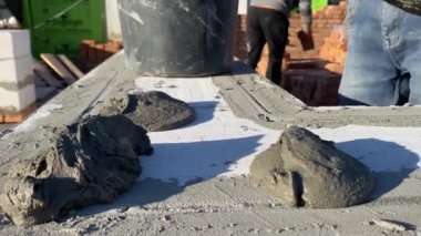 A male builder lays a foam block on a special mortar for laying blocks. The outer wall of the house from foam blocks. Construction of a private house