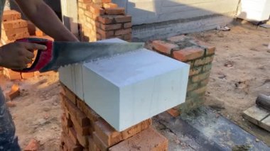 A male builder lays a foam block on a special mortar for laying blocks. The outer wall of the house from foam blocks. Construction of a private house