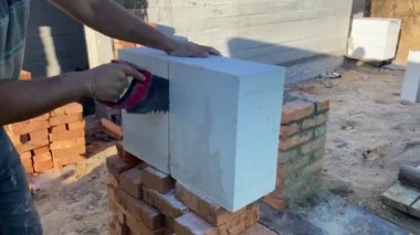 A male builder lays a foam block on a special mortar for laying blocks. The outer wall of the house from foam blocks. Construction of a private house