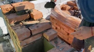 4k footage of a builder performing solid red brick masonry at a construction site using masonry mortar.