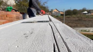 4k video footage of a male builder removing pieces of foam block from a cut strobe. Construction of a private house from a gas block, foam block.