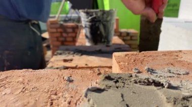 4k footage of a builder performing solid red brick masonry at a construction site using masonry mortar.