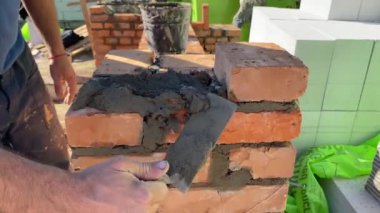 4k footage of a builder performing solid red brick masonry at a construction site using masonry mortar.