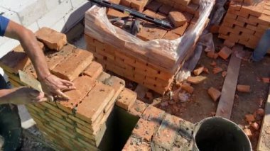 4k footage of a builder performing solid red brick masonry at a construction site using masonry mortar.