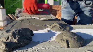 A male builder lays a foam block on a special mortar for laying blocks. The outer wall of the house from foam blocks. Construction of a private house