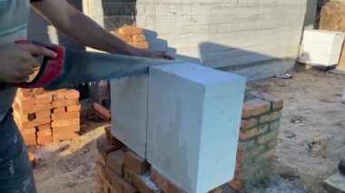 A male builder lays a foam block on a special mortar for laying blocks. The outer wall of the house from foam blocks. Construction of a private house