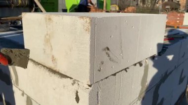 A male builder lays a foam block on a special mortar for laying blocks. The outer wall of the house from foam blocks. Construction of a private house