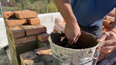 4k footage of a builder performing solid red brick masonry at a construction site using masonry mortar.