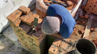 4k footage of a builder performing solid red brick masonry at a construction site using masonry mortar.