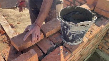 4k footage of a builder performing solid red brick masonry at a construction site using masonry mortar.