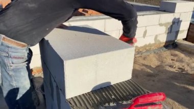 A male builder lays a foam block on a special mortar for laying blocks. The outer wall of the house from foam blocks. Construction of a private house