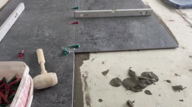 4k video footage of laying a large wide-format tile on a mounting mortar. Tiler laying tiles on cement mortar for gluing tiles on a surface