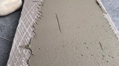 4k video footage of laying a large wide-format tile on a mounting mortar. Tiler laying tiles on cement mortar for gluing tiles on a surface