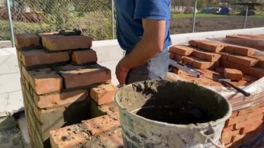 4k footage of a builder performing solid red brick masonry at a construction site using masonry mortar.