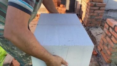 A male builder lays a foam block on a special mortar for laying blocks. The outer wall of the house from foam blocks. Construction of a private house