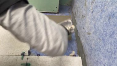 4k video footage of laying a large wide-format tile on a mounting mortar. Tiler laying tiles on cement mortar for gluing tiles on a surface
