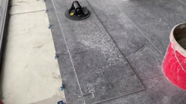 Yükselen bir havan mermisinin üzerine geniş formatlı fayans döşeme görüntüsü 4K. Bir yüzeye fayans yapıştırmak için çimento harcı döşeyen Tiler.