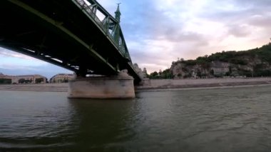 4k video footage of a river walk along the Danube in Budapest at sunset, Hungary. Sailing on a pleasure boat under the bridge