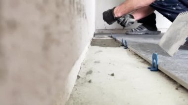 4k video footage of laying a large wide-format tile on a mounting mortar. Tiler laying tiles on cement mortar for gluing tiles on a surface