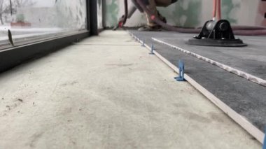 4k video footage of laying a large wide-format tile on a mounting mortar. Tiler laying tiles on cement mortar for gluing tiles on a surface