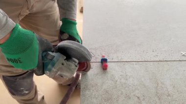 4k video footage of taking measurements for further cutting tiles using a diamond cutter. Laying tiles by a professional tiler in a modern interior.