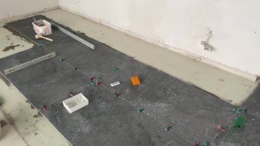 4k video footage of laying a large wide-format tile on a mounting mortar. Tiler laying tiles on cement mortar for gluing tiles on a surface