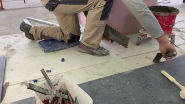 Yükselen bir havan mermisinin üzerine geniş formatlı fayans döşeme görüntüsü 4K. Bir yüzeye fayans yapıştırmak için çimento harcı döşeyen Tiler.