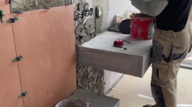 Yükselen bir havan mermisinin üzerine geniş formatlı fayans döşeme görüntüsü 4K. Bir yüzeye fayans yapıştırmak için çimento harcı döşeyen Tiler.