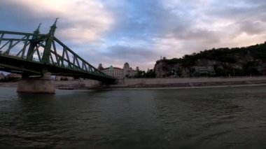 4k video footage of a river walk along the Danube in Budapest at sunset, Hungary. Sailing on a pleasure boat under the bridge