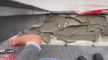 4k video footage of laying a large wide-format tile on a mounting mortar. Tiler laying tiles on cement mortar for gluing tiles on a surface